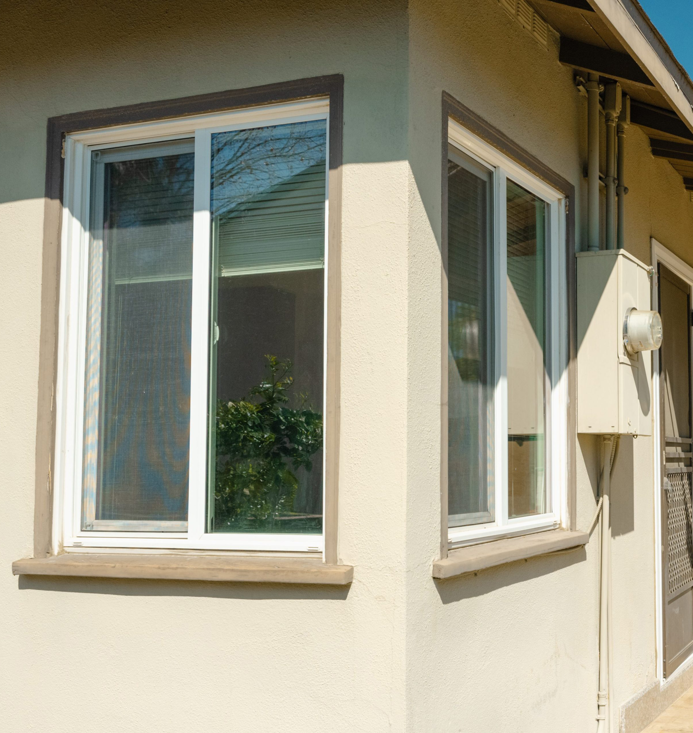 Imperial Series Horizontal Sliding Windows installed on the corner of a beige stucco home.